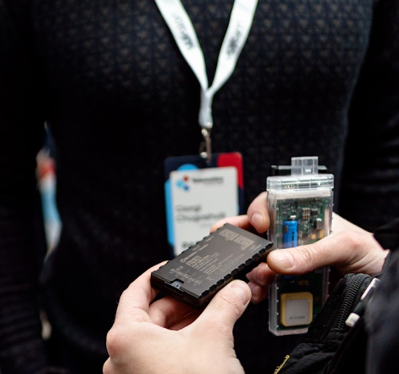 Hands holding a GPS tracking device and transparent IoT enclosure